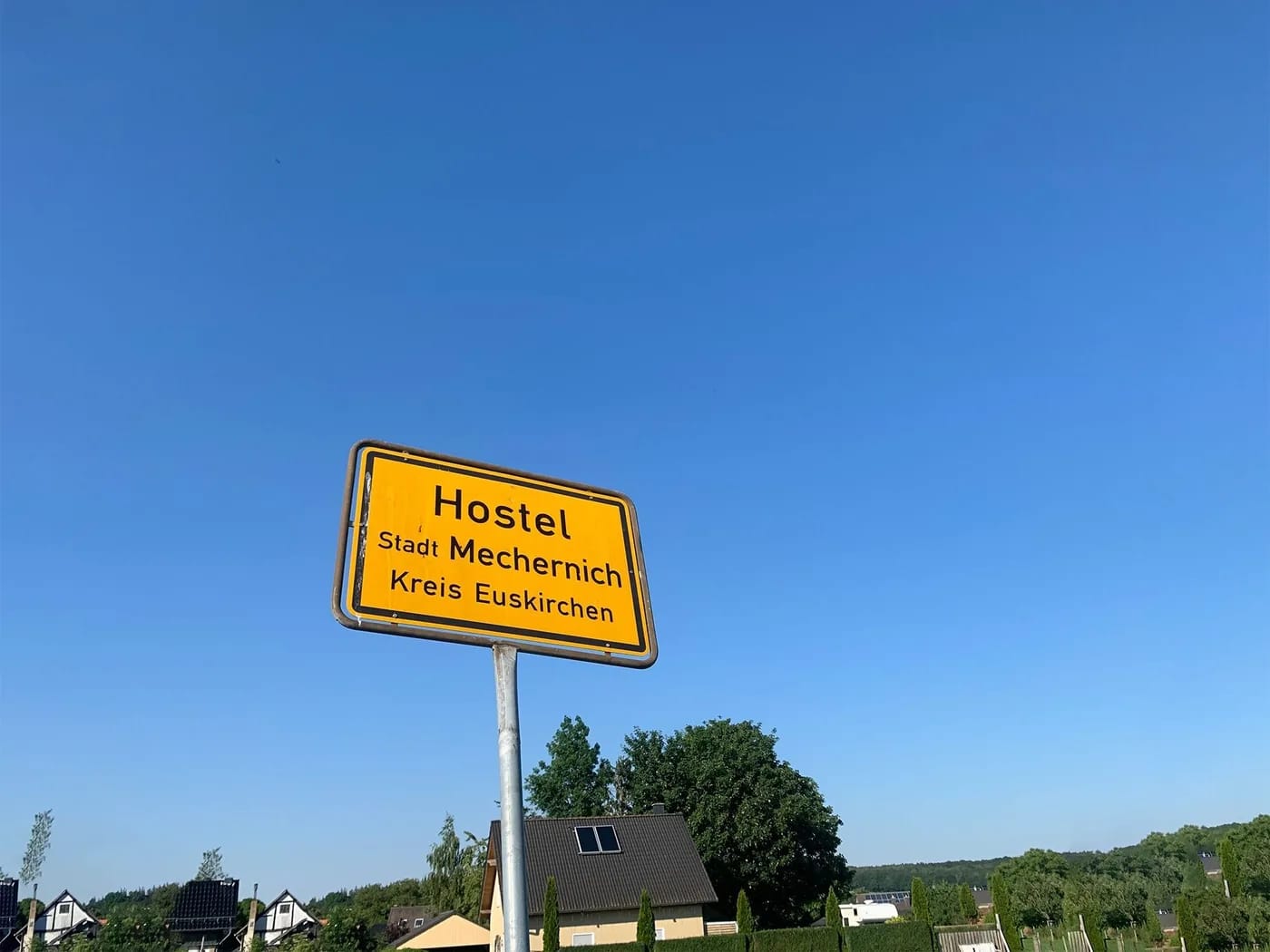 Das gelbe Ortsschild von Hostel bei Tag unter blauem Himmel