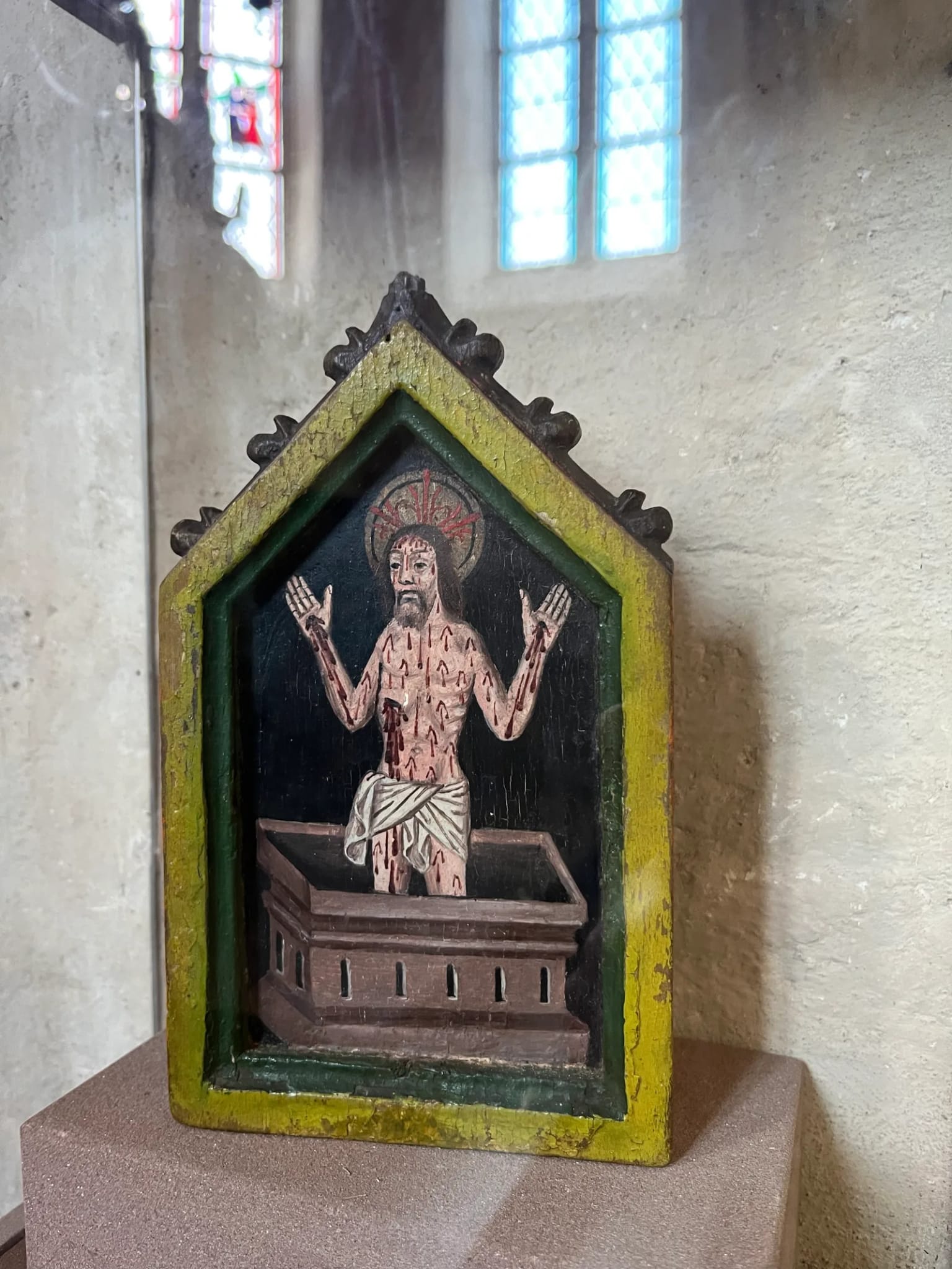Das Paxtäfelchen in seiner Vitrine: ein kleines, oben spitz zulaufendes Holztäfelchen mit dem Bild Christi als Schmerzensmann